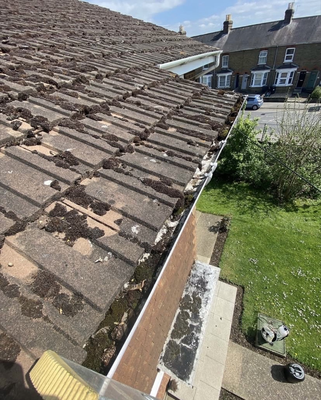 Before gutter clearance with moss build up on roof tiles