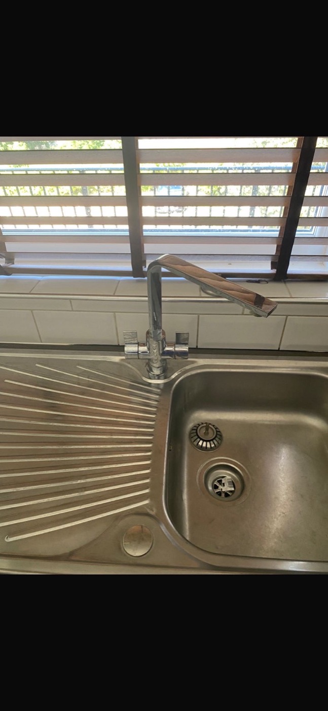 Before kitchen tap replacement with older chrome mixer tap above a stainless steel sink