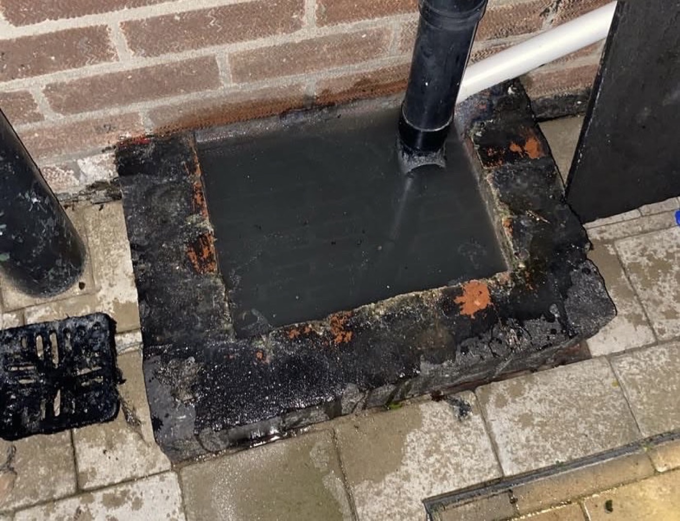Before outside drain access repair with the area temporarily sealed around the downpipe